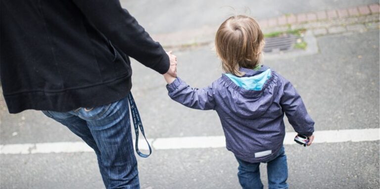 Eine Mutter hält ihren Sohn an der Hand.