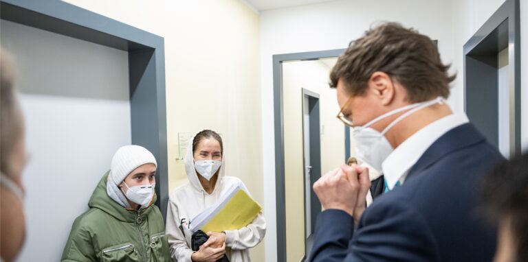 Nordrhein-Westfalens Ministerpräsident Hendrik Wüst (CDU, r) spricht in der zentralen Aufnahmestelle in Unna mit Flüchtlingen aus der Ukraine.