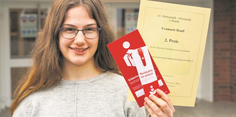 Die 15jährige Gymnasiastin zeigt ihre Urkunde für die erfolgreiche Teilnahme an der 61. Mathematik-Olympiade, bei der sie im Regionalwettbewerb den 2. Platz erreicht hat. Ebenfalls in der Hand hält sie zwei Dankeschön-Geschenke.