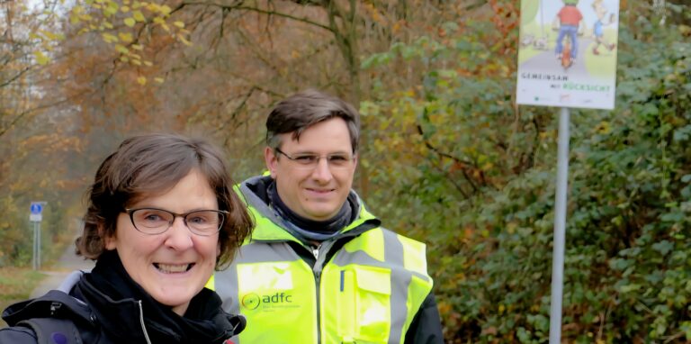 Mit Info-Plakaten wie im Hintergrund fordern Stadt Herten und Allgemeiner Deutscher Fahrradclub – hier Anja Thomas (Stadtplanung) und ADFC-Sprecher Patrick Berner – Radfahrer und Fußgänger auf der „Allee des Wandels“ zur gegenseitigen Rücksichtnahme auf.