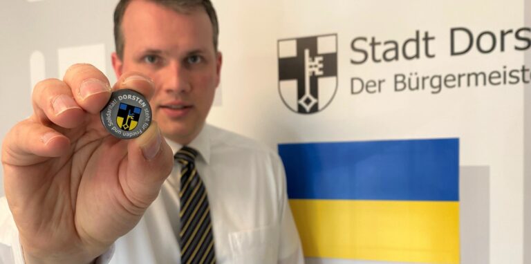 Bürgermeister Tobias Stockhoff zeigt den Dorsten-Ukraine-Button, der seit Dienstag in der Stadtinfo erhältlich ist.