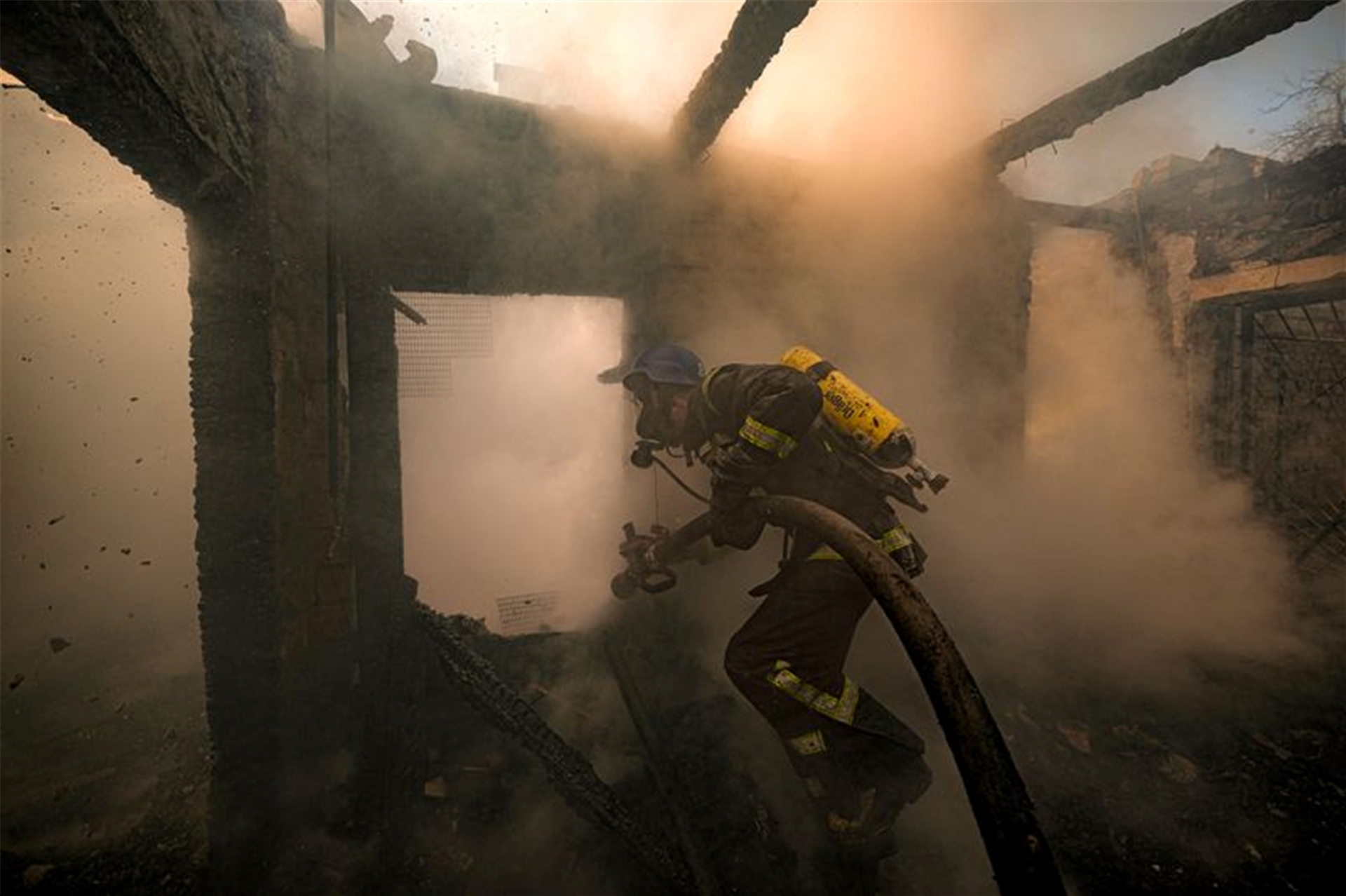 Ein ukrainischer Feuerwehrmann bei Löscharbeiten in einem nach russischen Angriffen zerstörten Haus in Kiew.