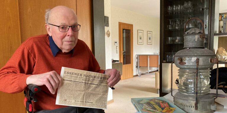Werner Dickhöfer zeigt eine alte Zeitung mit Berichten über den Bombenkrieg im Ruhrgebiet.