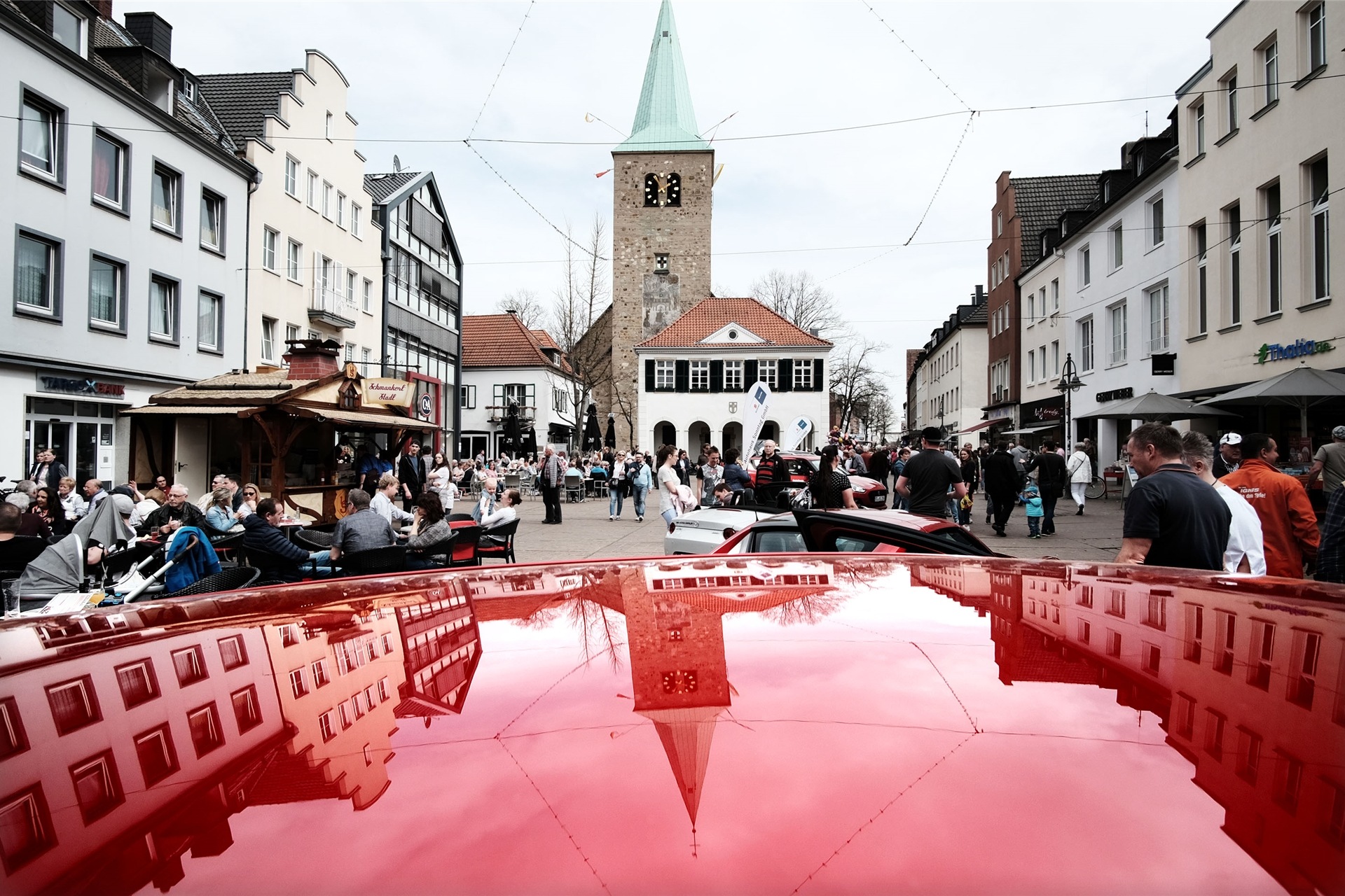 Die Silhouette der Altstadt spiegelt sich auf der Motorhaube eines Autos auf dem Marktplatz in Dorsten.