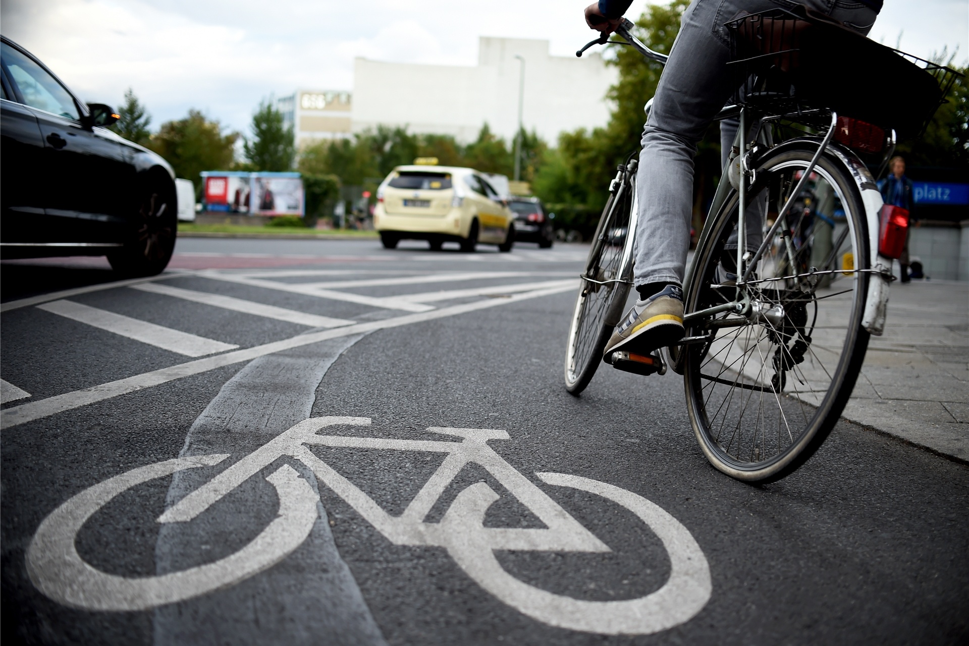 Ein Fahrradfahrer benutzt einen Radweg, im Hintergrund fahren Autos vorbei.