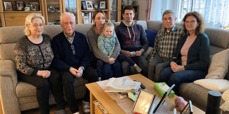 Die Flüchtlinge und ihre Gastgeber sitzen auf dem Sofa im Wohnzimmer von Familie Krasontovitsch