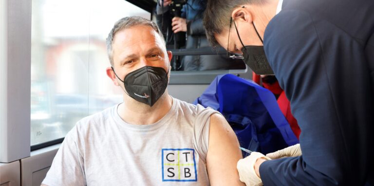 Bundesgesundheitsminister Karl Lauterbach (r) impft einen Mann im Tour-Bus der Initiative #ImpfenHilft. #ImpfenHilft ist eine bundesweite Initiative, um Menschen zu erreichen, die noch skeptisch sind, sich gegen Covid-19 impfen zu lassen.