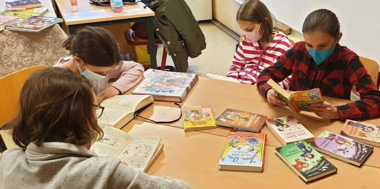 Vier Kinder sitzen in einem Klassenraum des Willy-Brandt-Gymnasiums in Oer-ERkenschwick um einen Tisch und lesen Bücher.