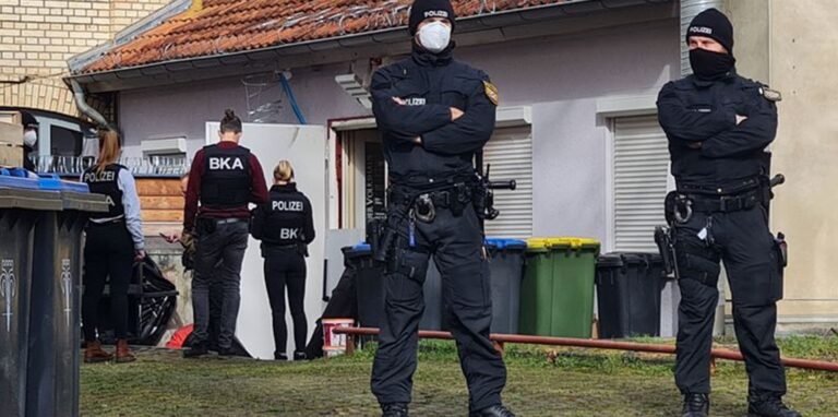 Polizisten vor einem Hintereingang eines Gebäudes in Eisenach, das sie durchsuchen.