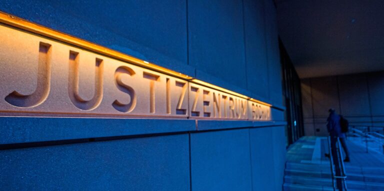 Beleuchteter Schriftzug des Justizzentrums Bochum in der Dämmerung. Ein 45-jähriger Mann ist nach einer Attacke mit einer Eisenstange auf seine 74-jährige Mutter freigesprochen worden. Der psychisch schwer kranke Sohn hatte ihr das Gesicht zertrümmert.