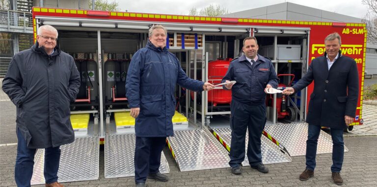 Ekkehard Grunwald, Erster Beigeordneter, Claus Beeking, Ausschussvorsitzender für Ordnung, Feuerwehr und Katastrophenschutz, Thorsten Schild, Leiter der Feuerwehr und Bürgermeister Christoph Tesche stehen vor einem etwa fünf Meter langem, geöffneten Container mit technischen Geräten darin.