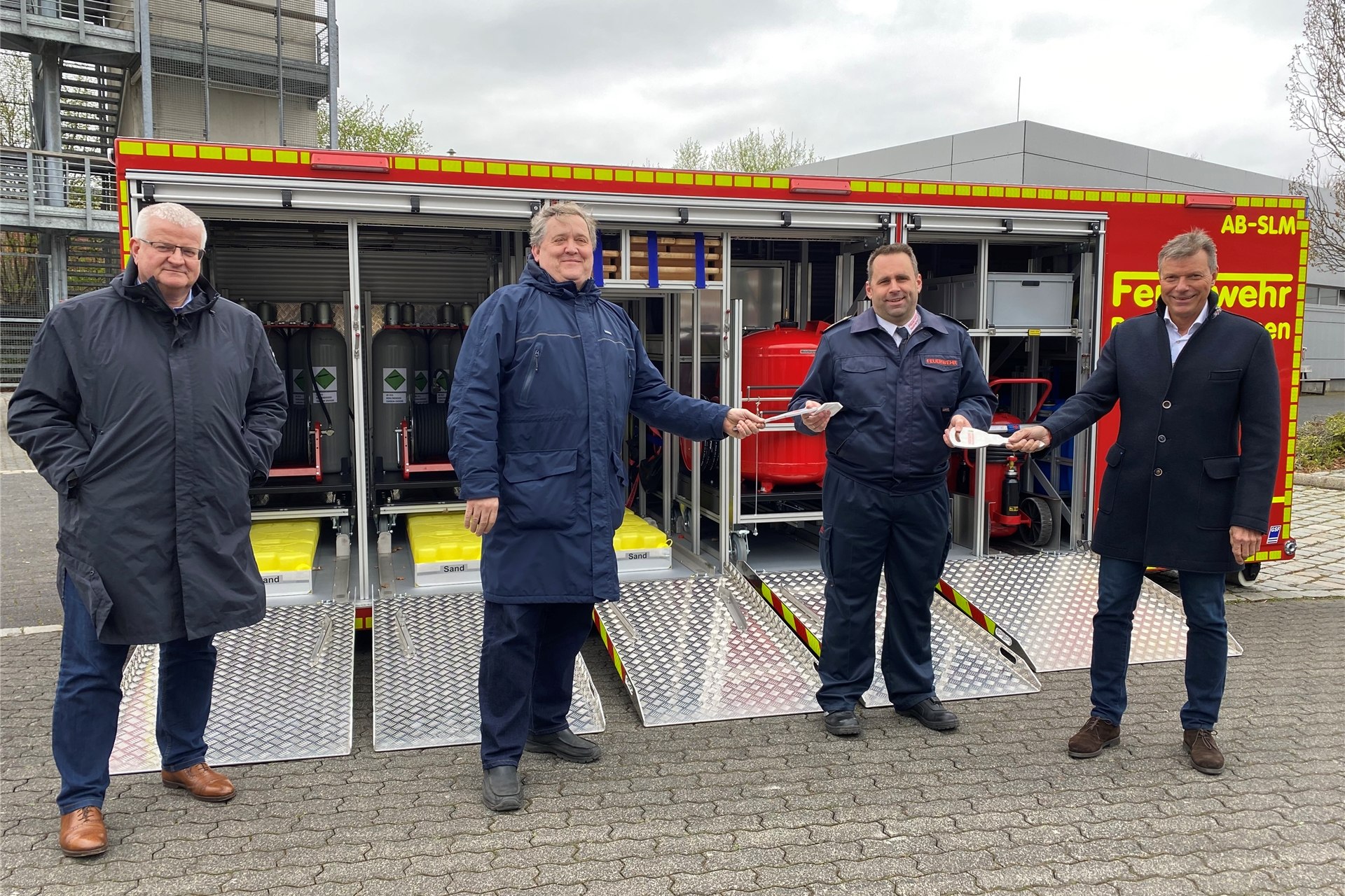 Ekkehard Grunwald, Erster Beigeordneter, Claus Beeking, Ausschussvorsitzender für Ordnung, Feuerwehr und Katastrophenschutz, Thorsten Schild, Leiter der Feuerwehr und Bürgermeister Christoph Tesche stehen vor einem etwa fünf Meter langem, geöffneten Container mit technischen Geräten darin.