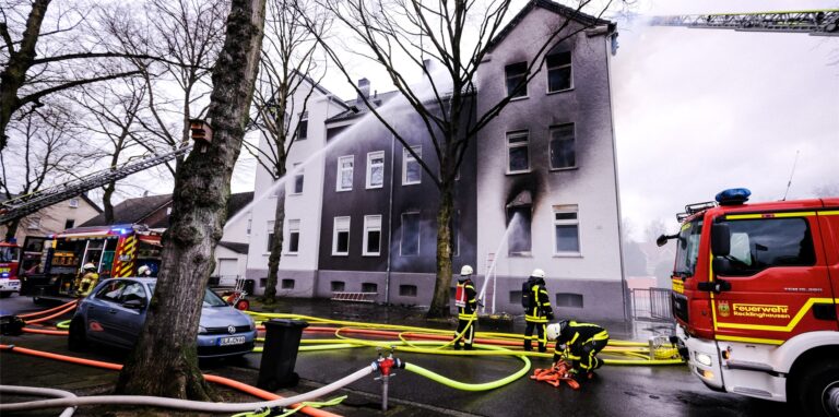 Eine Drehleiter der Feuerwehr steht vor einem brennenden Haus an der Grillostraße in Recklinghausen.