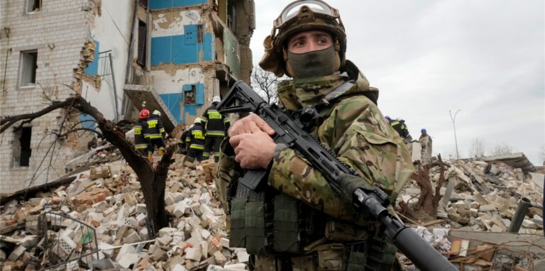 Ein ukrainischer Soldat steht mit seinem Gewehr vor einem durch russischen Beschuss zerstörten Wohnhaus in Borodjanka. Die Kleinstadt in der Nähe von Kiew soll Schauplatz noch schlimmerer Kriegsverbrechen geworden sein, als Butscha.
