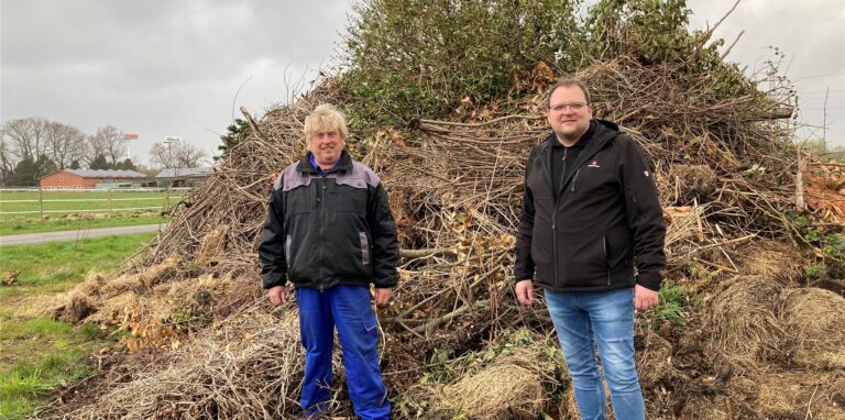 Osterfeuer in Recklinghausen: Landwirt Heribert Merten (links) und Nico Heinemann von der Bürgerschützengilde Röllinghausen-Berghausen stehen vor dem Haufen für das Osterfeuer, der sich auf einem Feld befindet.