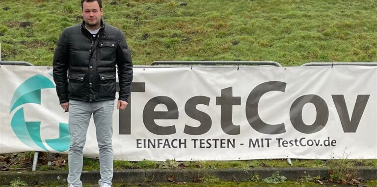 Patrick Schürhoff vor dem Banner „TestCov“