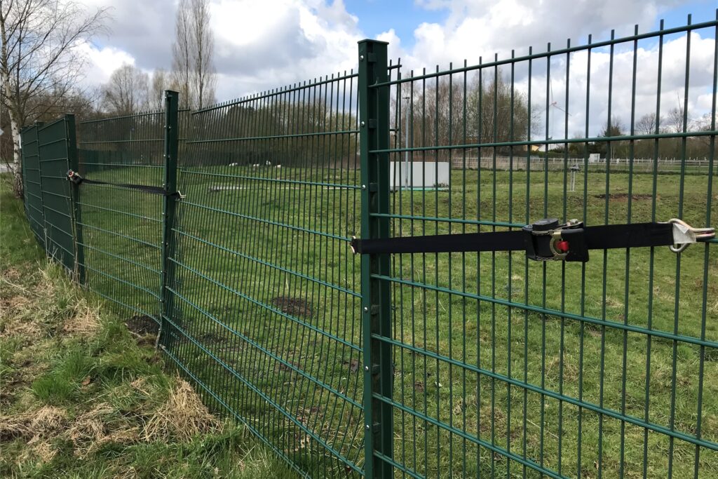 Der Zaun am Hellweg ist beschädigt, im Gras sind noch die Reifenspuren zu sehen.