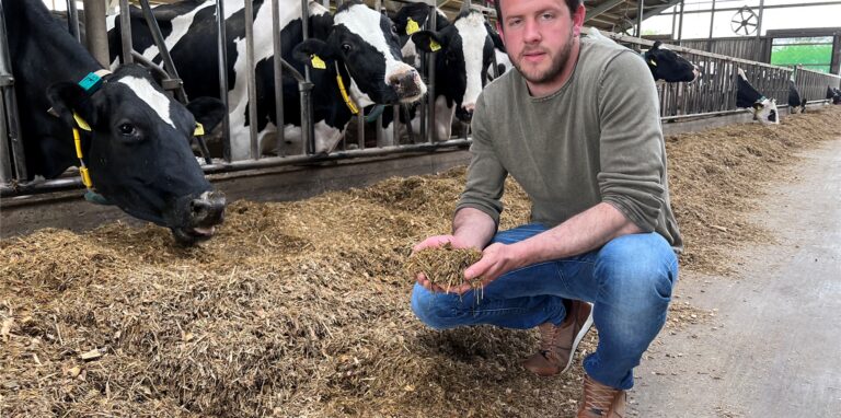 Milchbauer Johannes Thier aus Lembeck sitzt vor den Kühen seines Betriebes und hält deren Futter in der Hand.