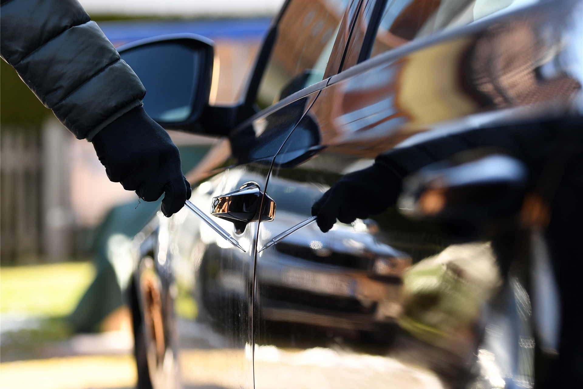 Ein Mann steht mit einem Schraubenzieher neben einem Auto (Symbolfoto).