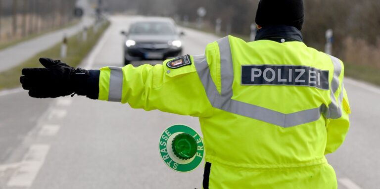 Ein Polizist hält auf einer Straße ein Fahrzeug an