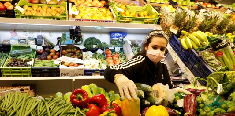 Eine Frau sortiert Gemüse in einem Supermarkt.