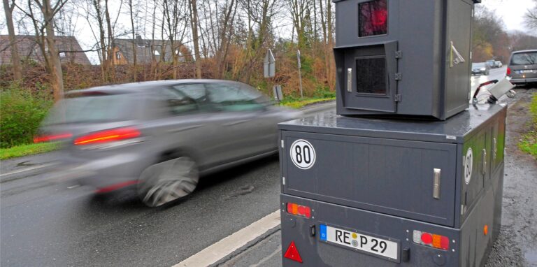 Der sogenannte Panzerblitzer steht an einer Straße, ein Auto fährt vorbei.