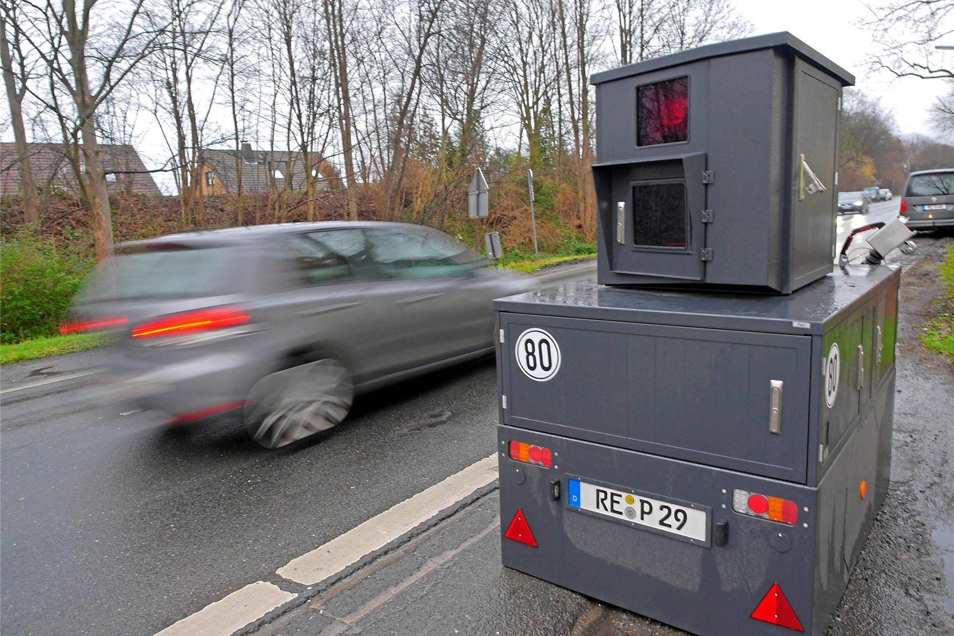 Der sogenannte Panzerblitzer steht an einer Straße, ein Auto fährt vorbei.