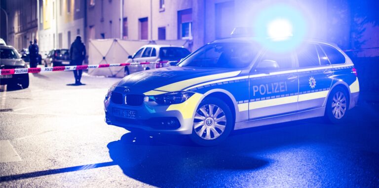 Ein Streifenwagen der Polizei steht vor einer Häuserreihe.