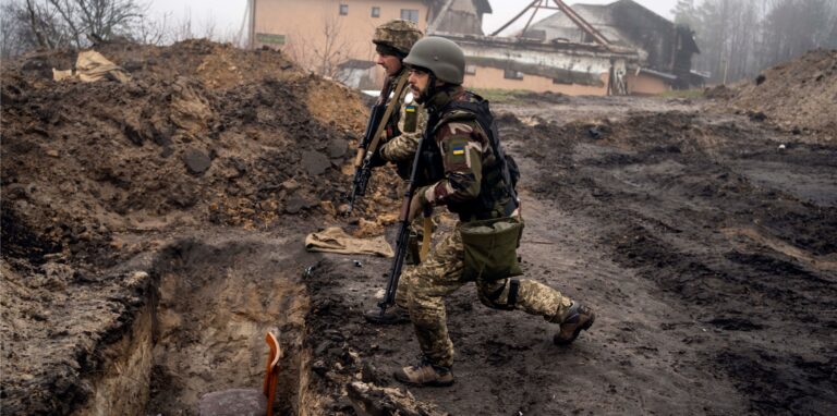 Ukrainische Soldaten nähern sich einem Graben, den russische Soldaten bei der Rückeroberung eines Gebiets am Stadtrand von Kiew benutzt hatten.