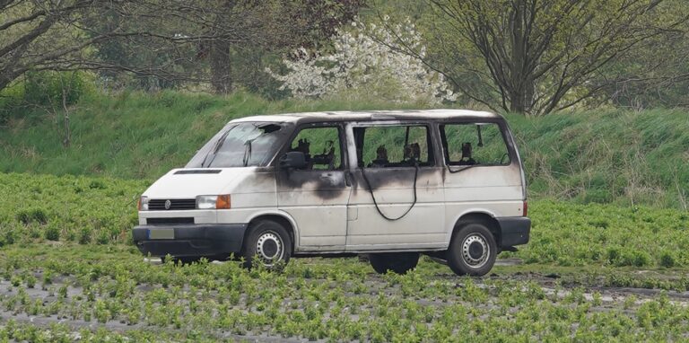 Ein weißer VW-Transporter, in dem ein Feuer gewütet hat, steht in einem Feld in Waltrop.