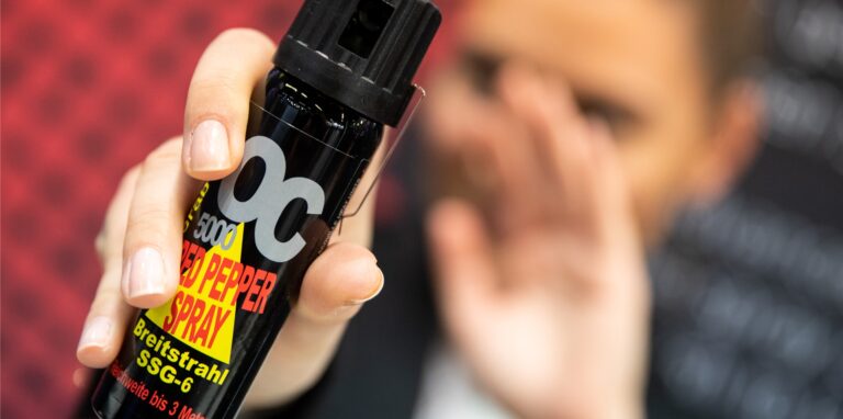 Eine Frau hält eine Dose Pfefferspray in der Hand.