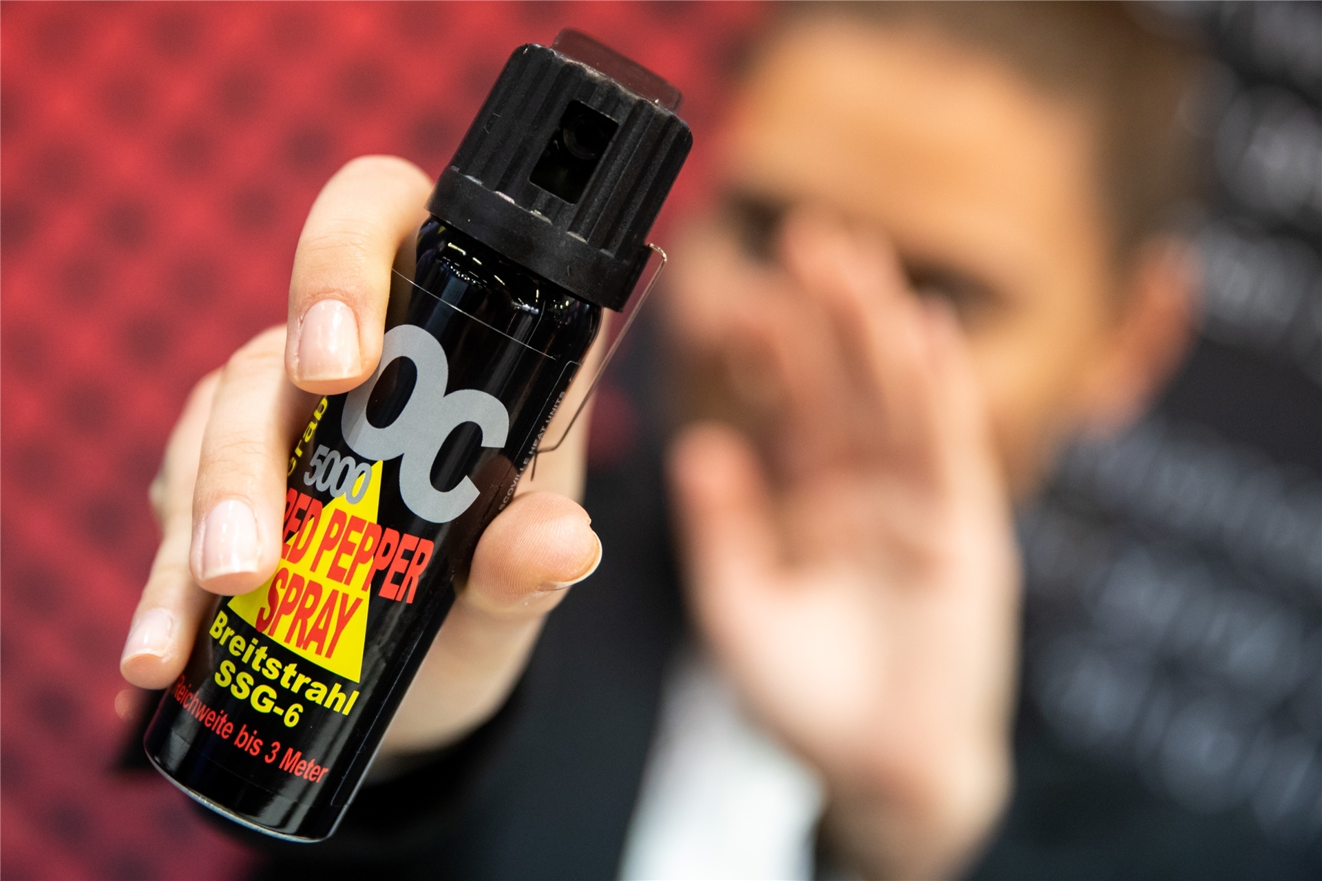 Eine Frau hält eine Dose Pfefferspray in der Hand.