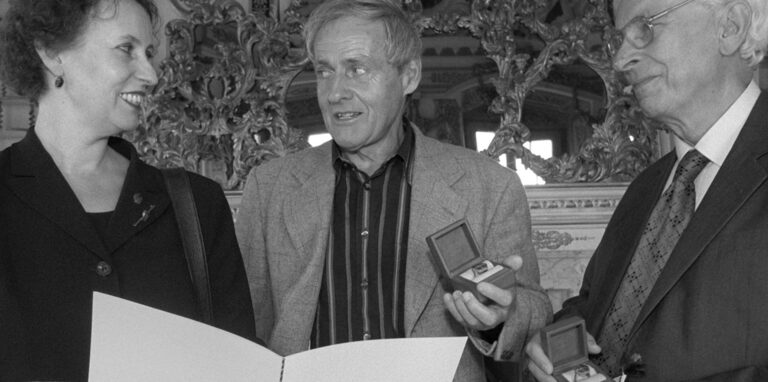 Ein schwarz-weiß Foto: Drei Menschen sind zu sehen, links eine Dame, rechts zwei Herren. Der mittlere ist Karl Ganser. Er hält den Deutschen Preis für Denkmalschutz in der Hand.