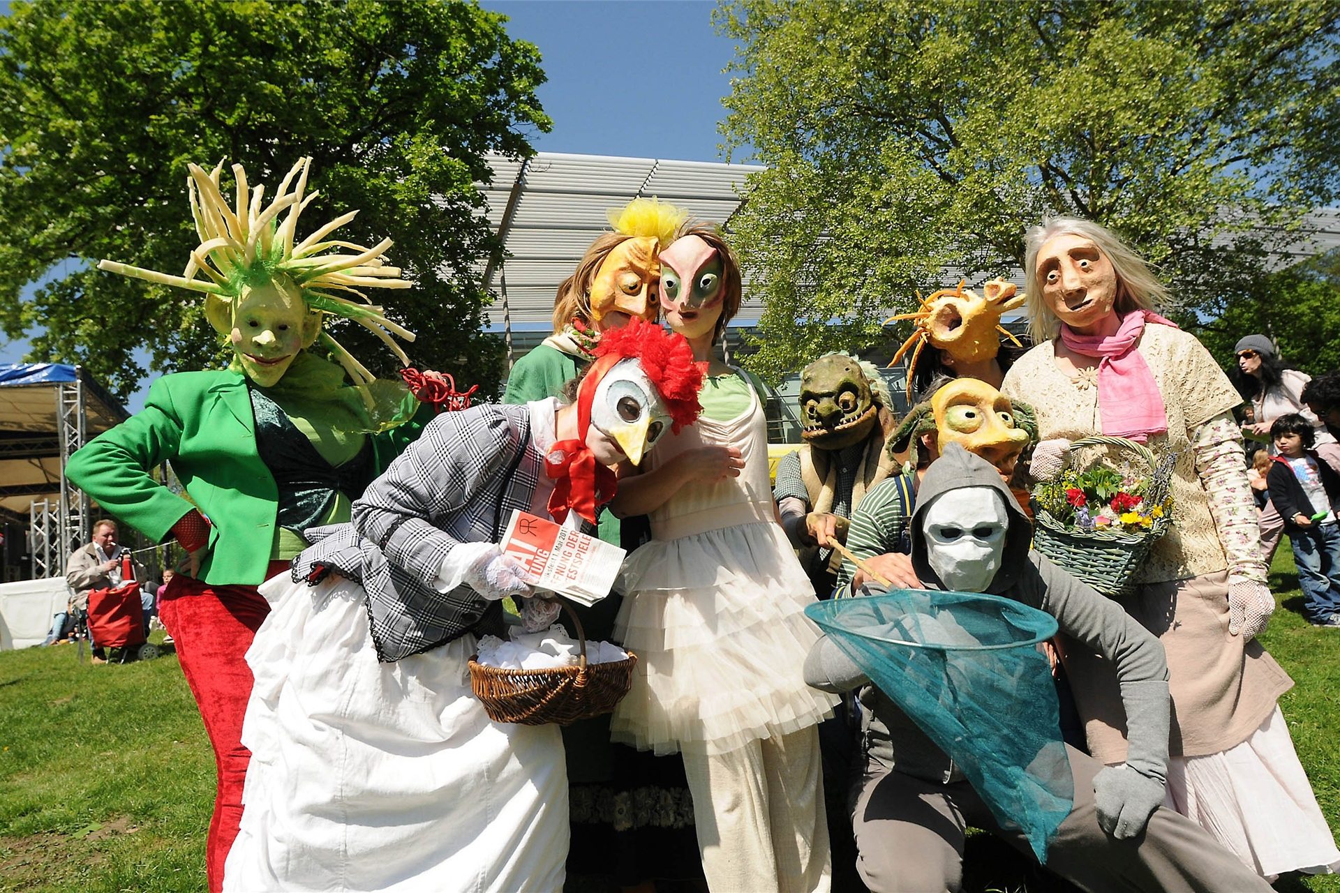 Neun völlig verkleidete Künstler stehen vor dem Festspielhaus in Recklinghausen auf der grünen Wiese und schauen in die Kamera.