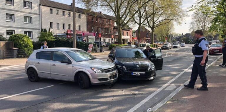 Zwei Autos, die ineinander gefahren sind, stehen auf der Castroper Straße in Datteln. Ein Polizist steht daneben.