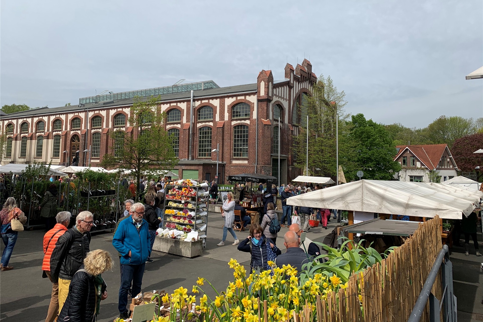 Die Gebäude von Manufactum auf dem alten Zechengelände Waltrop bilden die Kulissen für diverse Pflanzen-Marktstände der „Gartentage“. Einige Leute schauen sich um.