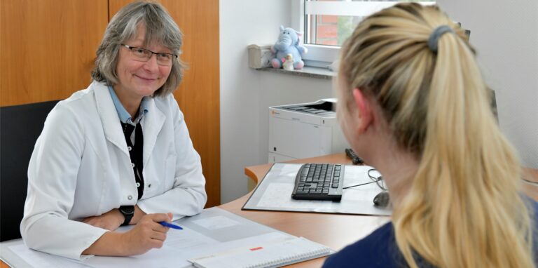 Dr. Simone Sowa sitzt am Schreibtisch und spricht mit einer Patientin.