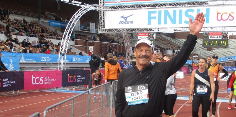 Der Waltroper Gerd Pszolla steht im Amsterdamer Stadion, wo der Zieleinlauf des Marathons war. Im Hintergrund Zuschauer und weitere Läufer.