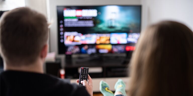 Ein Paar sitzt vor dem Fernseher und guckt Netflix.