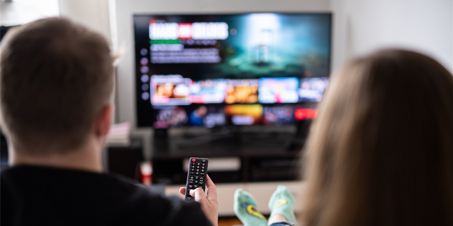 Ein Paar sitzt vor dem Fernseher und guckt Netflix.