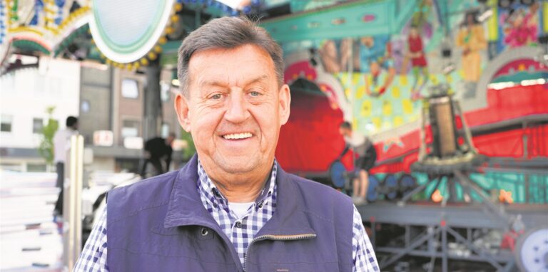 Schausteller Richard Abendroth steht vor einem Karussell.