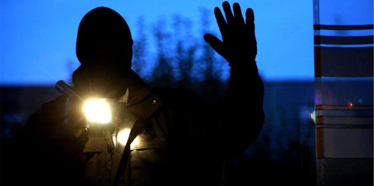 Ein vermummter Mann mit einer Taschenlampe in der Hand.