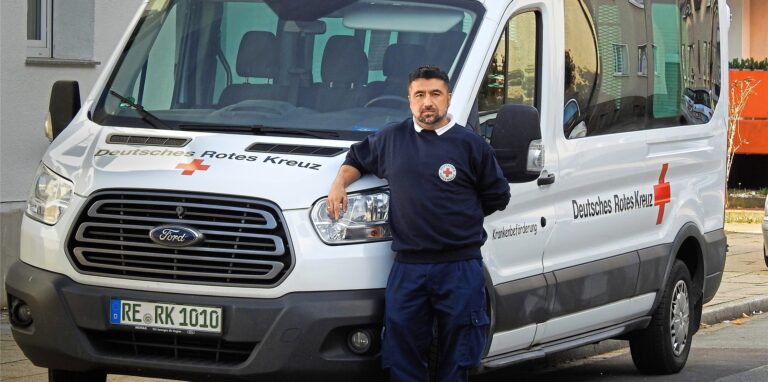 Ercan Kök, Fahrdienstleiter beim DRK-Ortsverband Westerholt/Bertlich, steht vor einem der Transporter.