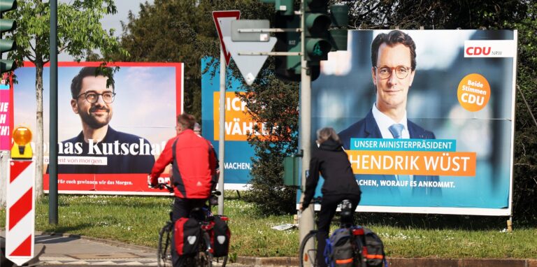 Wahlplakate mit Portraits der Spitzenkandidaten von CDU, Ministerpräsident Hendrik Wüst (r) und SPD, Thomas Kutschaty (l), stehen auf einer Wiese. In Nordrhein-Westfalen ist am 15. Mai 2022 Landtagswahl.