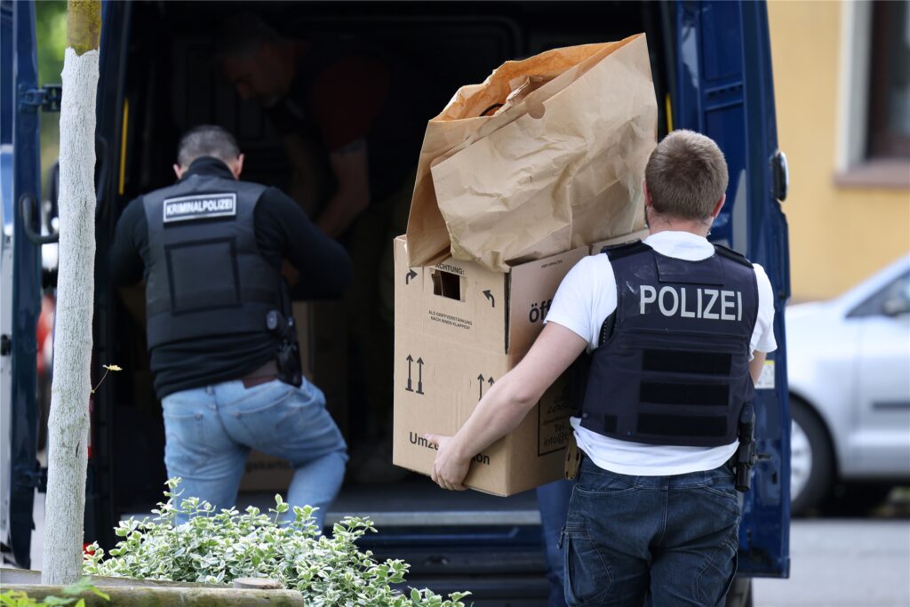 Polizisten tragen Gegenstände aus dem Wohnhaus des Tatverdächtigen.