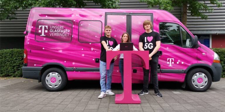 Drei Menschen stehen vor einem Transporter in Magenta-Farben – ein Infomobil der Telekom.