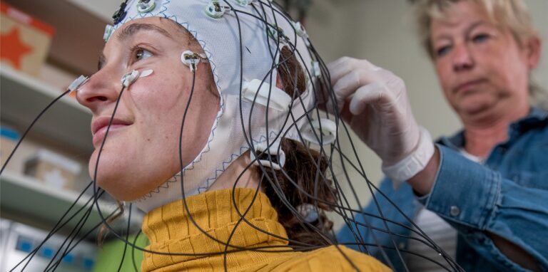 Die medizintechnische Assistentin Gabi Schöns richtet eine Haube mit Elektroden zur Messung der Hirnströme im Labor für Neurobiologie am Leibniz-Institut bei einer Probandin ein.