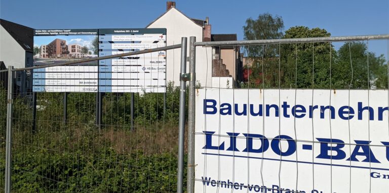 Baustellenschilder am Bauzaun und dahinter