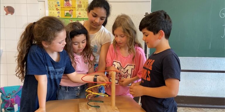 Fünf Kinder stehen um ein Modell einer Gewaltspirale.