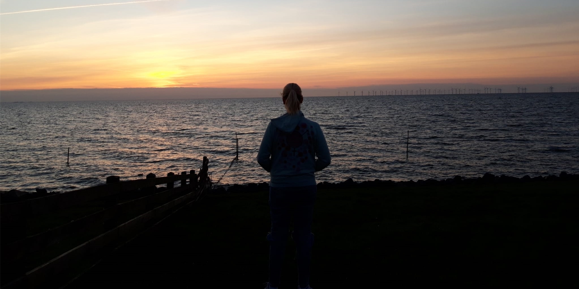Die 19-jährige Sonya aus Haltern steht am Meer vor einem Sonnenuntergang.